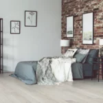 Spacious brick wall bedroom interior with a bed and two paintings | Reinhold Flooring